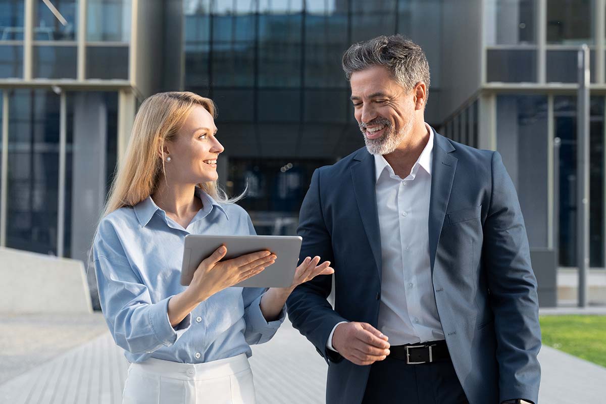 Business colleagues walking outside holding a tablet