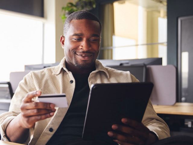 Man using a credit card and tablet in an office