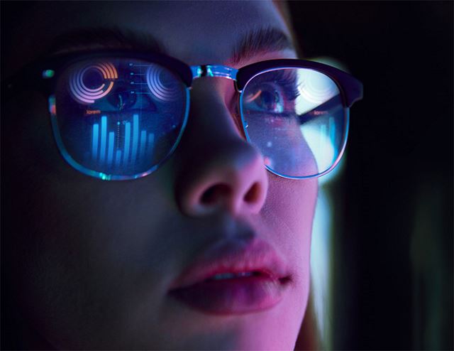 Woman looking up with graphs and charts reflected in her glasses