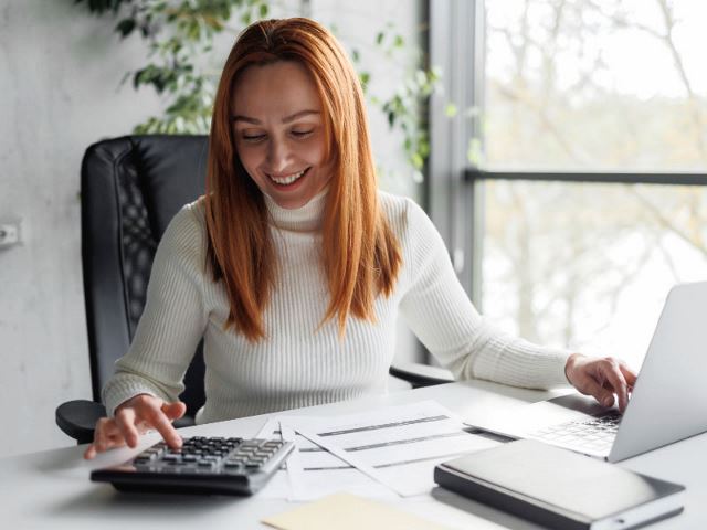 Woman using a calculator and computer in her office