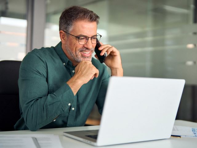 Professional man talking on the phone and looking at laptop