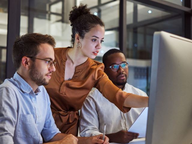 Three professionals working at a computer together