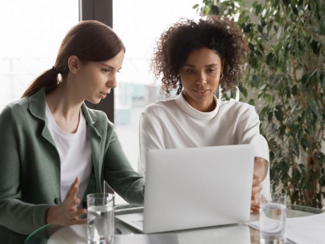 Two female colleagues looking at a laptop together