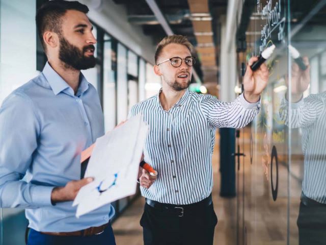 Two colleagues discussing and writing on a whiteboard