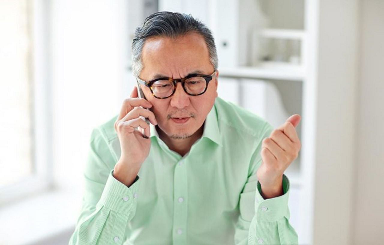 Professional older man talking on cell phone in home office