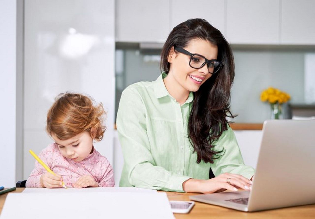 Young professional mother working from home with young child