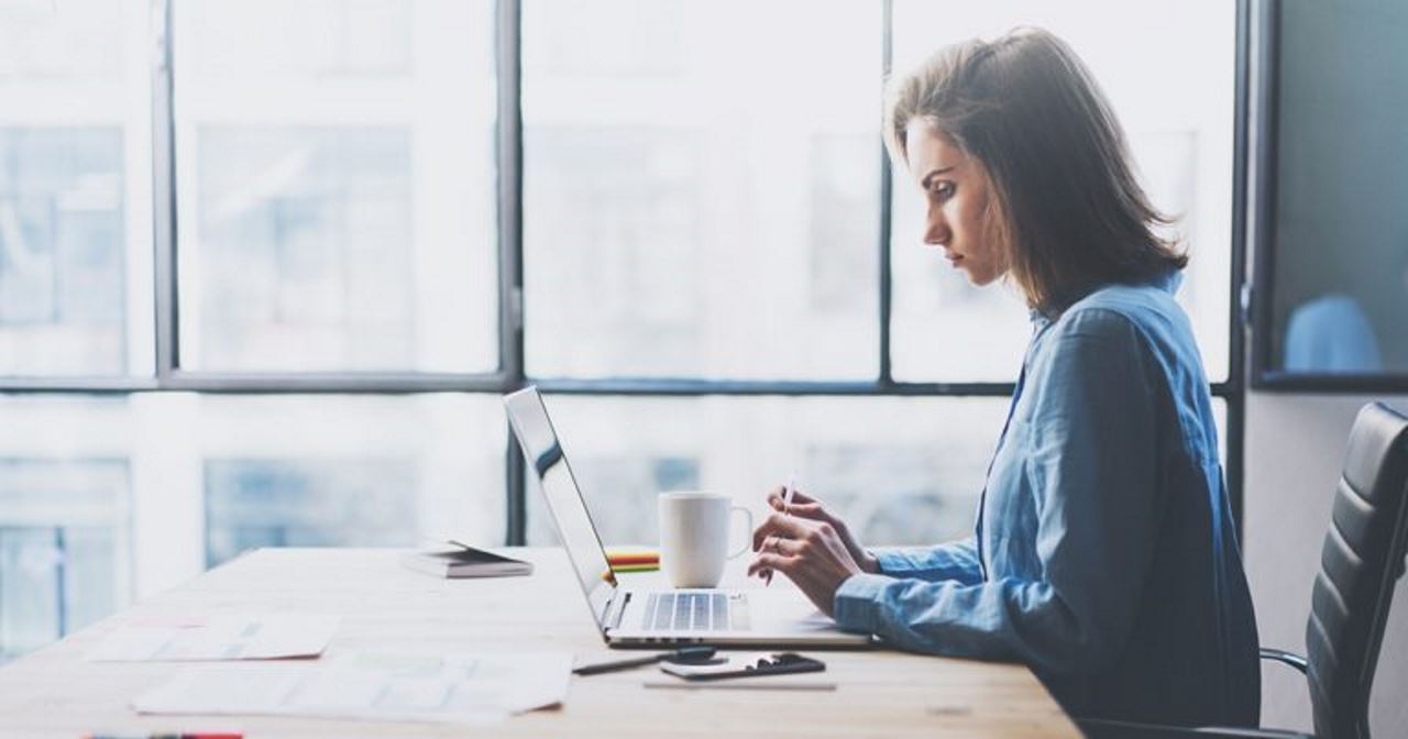 Business woman working on laptop in bright office