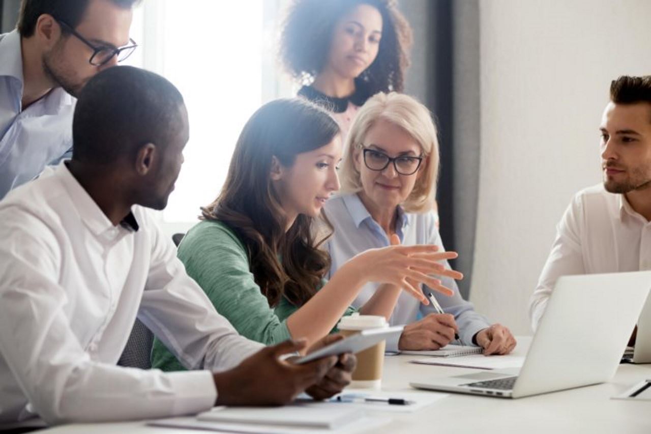 employees meeting in an office gathered in front of a laptop