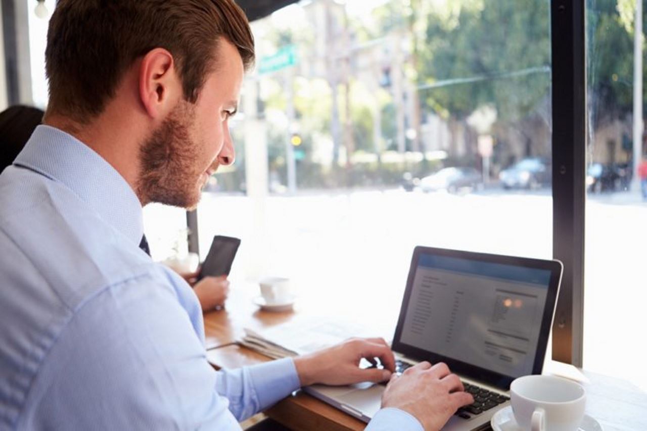 homme travaillant sur un ordinateur portable dans un café