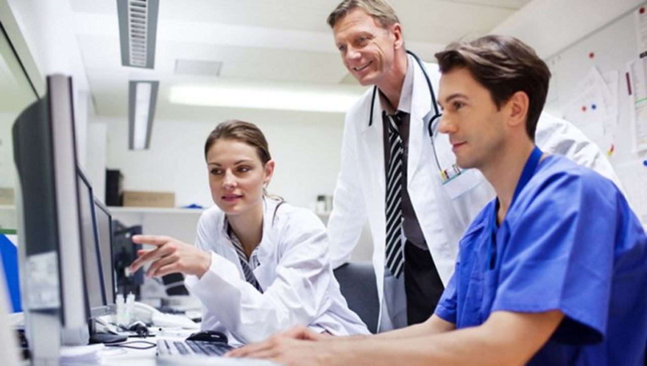 A staff of two doctors and a nurse reviewing data on a computer monitor