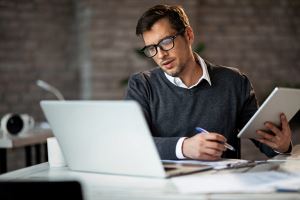 man kijkt naar een laptop en checkt zakelijke financiële gegevens