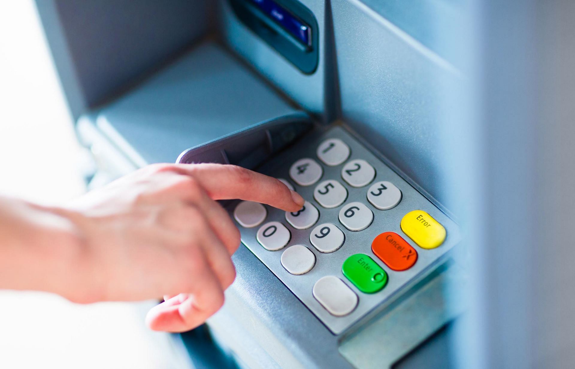 hand pressing buttons on an ATM machine