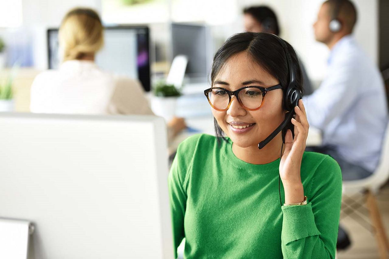 Call center employee talking to customer, touching her headset