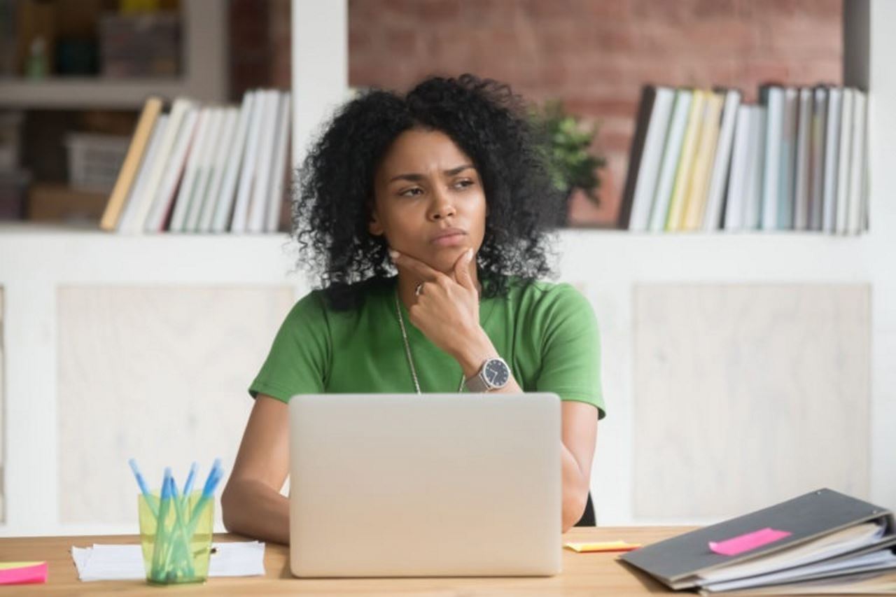 customer dissatisfaction-woman sitting in an office in front of a laptop with her left hand on her chin