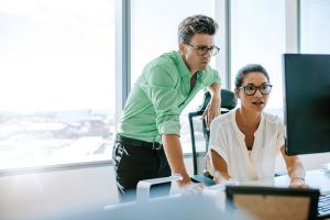 Homme et femme regardent un écran d'ordinateur avec des FAQ sur la trésorerie à l'écran