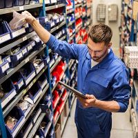 Man in magazijn met auto-onderdelen kijkt naar tablet