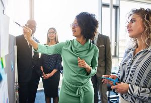 Zakenvrouw die naar een whiteboard wijst en met collega's praat