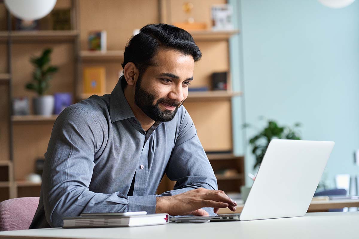 South Asian man using laptop in modern office